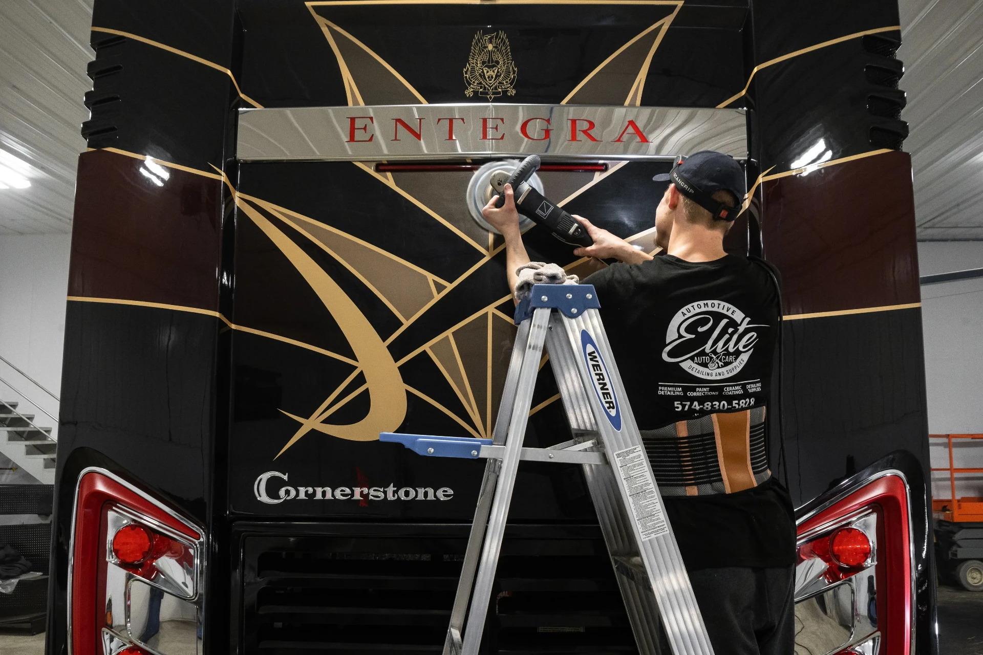 Elite Auto Care technician polishing the rear of a large motorcoach