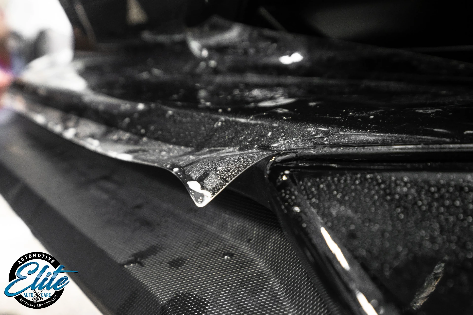 Protective film edge detail on a dark vehicle panel