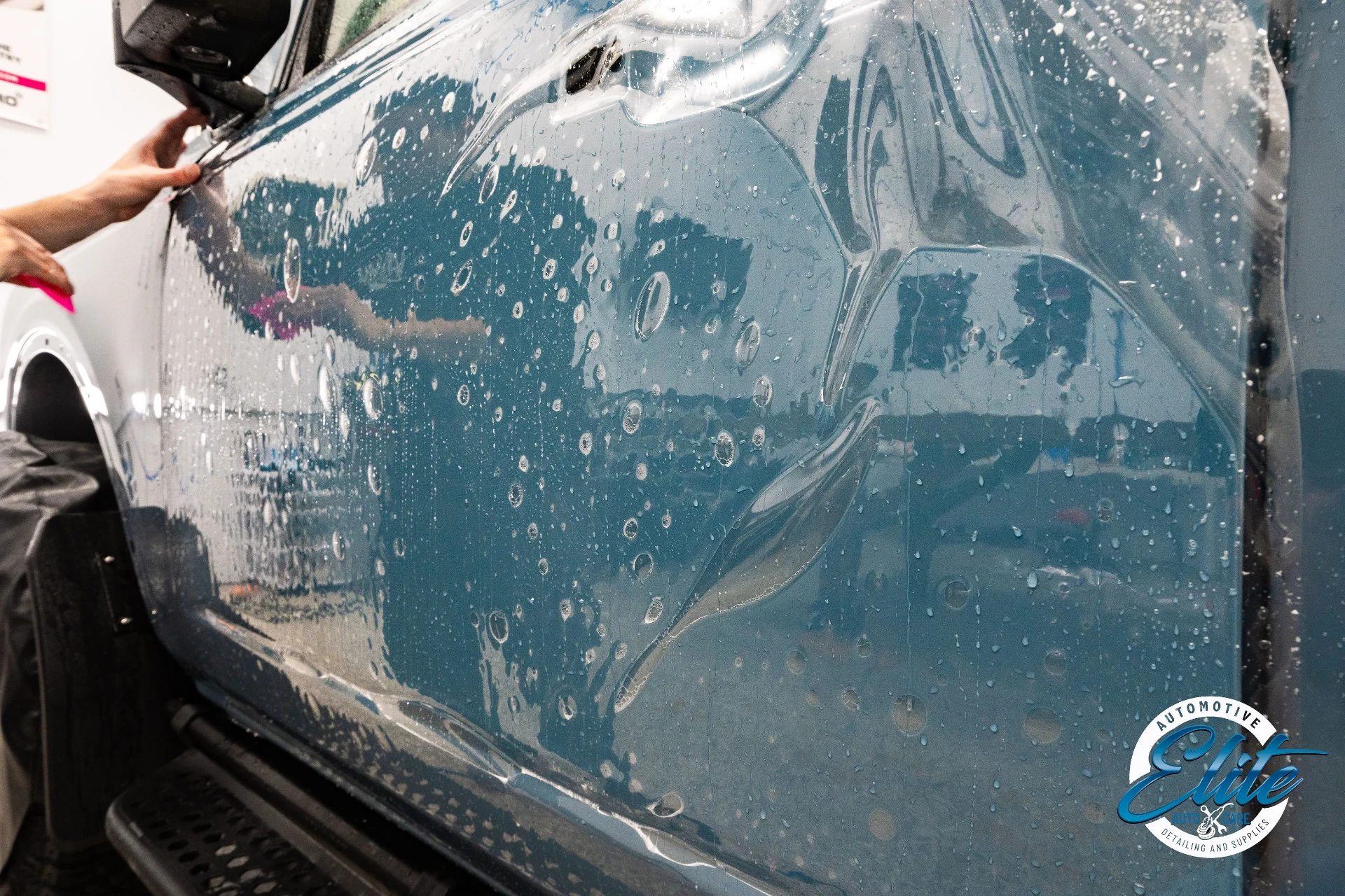 Technician squeegeeing paint protection film onto a vehicle door panel