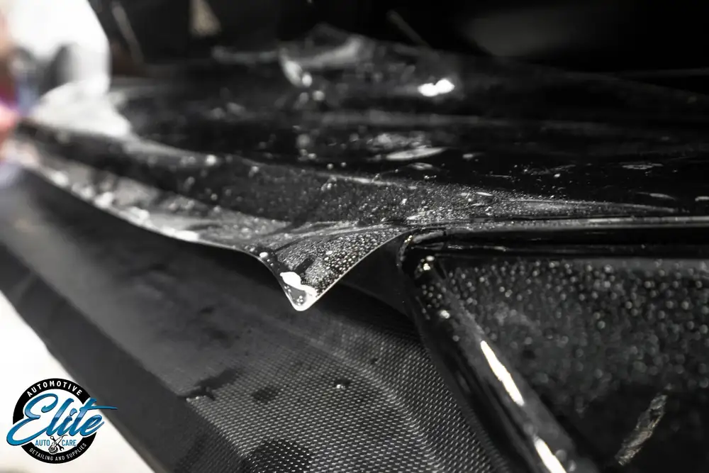 Protective film edge detail on a dark vehicle panel