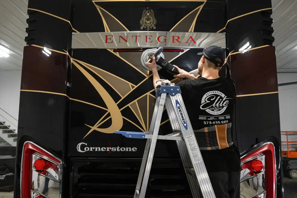 Elite Auto Care technician polishing the rear of a large motorcoach